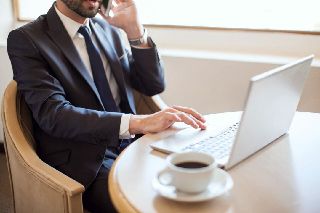A man calling from his phone while using his laptop A man calling from his phone while using his laptop